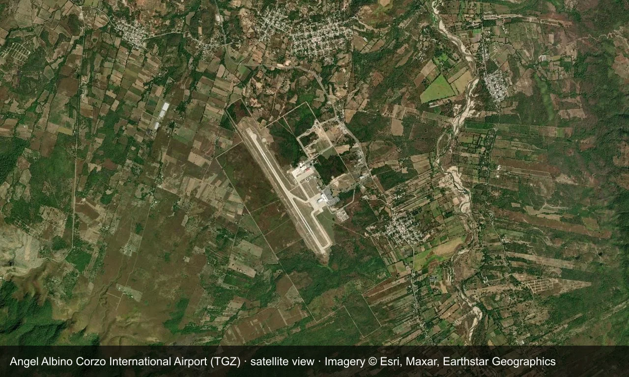 Satellitenansicht: Die Startbahn von Tuxtla Gutiérrez liegt in einem Tal in Chiapas, Terminal und Vorfeld daneben, Berge und Ackerland ringsum.