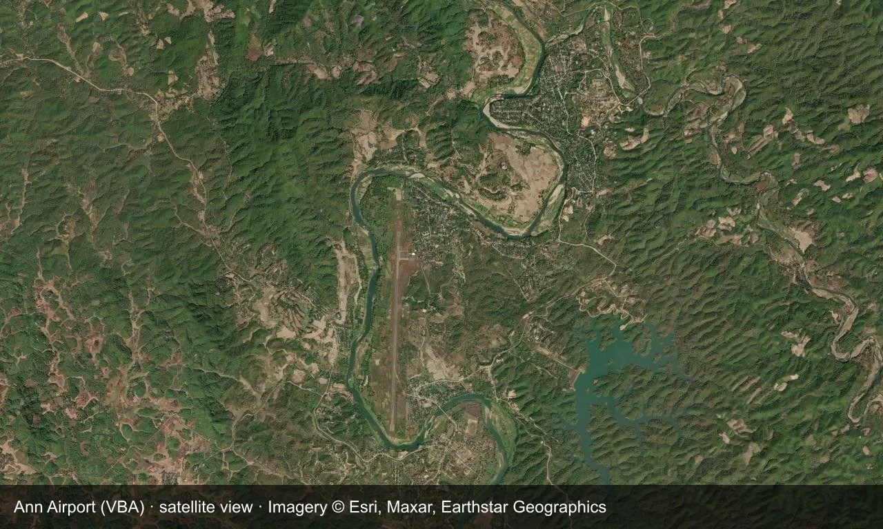 Satellitenansicht: Eine Startbahn führt durch grüne Hügel im Zentrum Myanmars, mit einem kleinen Vorfeld und einem Terminal daneben.